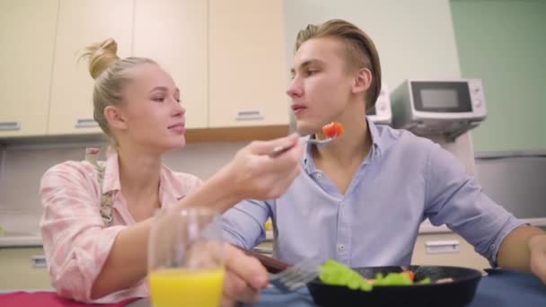 Mujer joven alimenta a su marido huevos revueltos — Vídeos de Stock